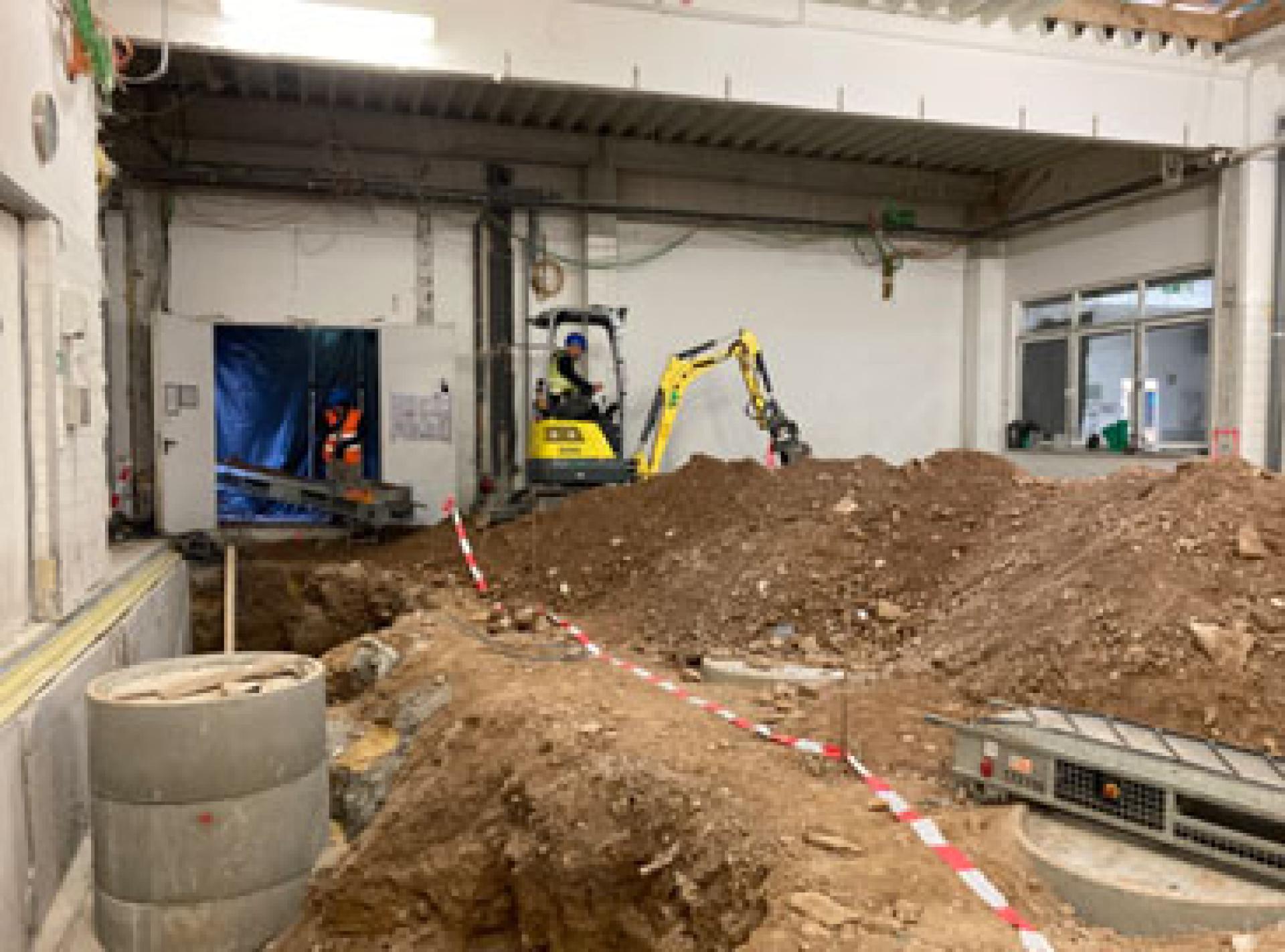 A room with a digger at one end, with mounds of turned earth
