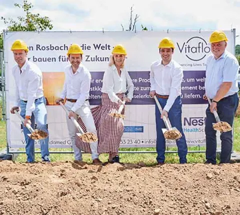 Group of people in hardhats, holding spades with soil, breaking ground for the Rosebach redevelopment